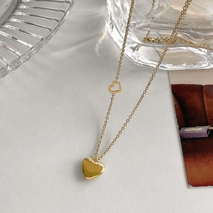 Detail of a gold heart pendant necklace on white textured surface with retro card