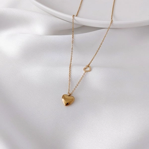Elegant gold titanium heart necklace with solid and hollow pendants on white silk