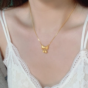 Collier élégant en or 18 carats avec pendentif nœud et muguet porté par un mannequin femme