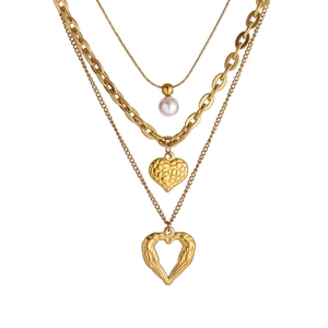 Gold layered chain necklace with white pearl and vintage heart pendants on white background