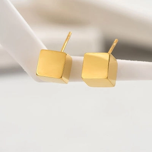 Detalle de los pendientes de cubo en acero chapado en oro de 14k con acabado pulido espejo