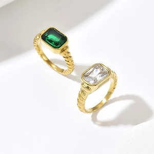 Detail eines gedrehten Goldrings mit smaragdgeschliffenen grünen und klaren Steinen