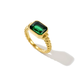 Detail eines gedrehten Goldrings mit smaragdgrünem rechteckigem Stein in Makroansicht
