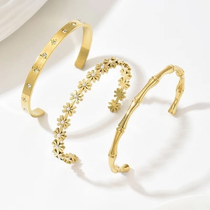 Dettaglio di tre bracciali in acciaio inossidabile placcati oro 14k con texture margherita e bambù