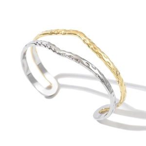 Detalle de brazalete abierto bicolor en acero inoxidable chapado en oro 14K martillado