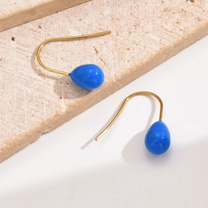 Detailaufnahme glänzender blauer Tropfenohrringe mit goldenen Haken auf Steinständer