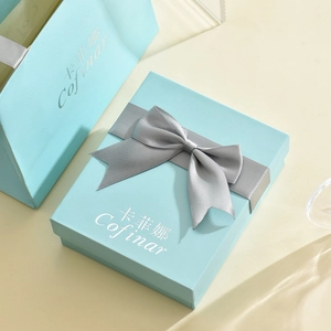 Primer plano de caja de regalo para joyas azul claro y bolsa con lazo de satén gris
