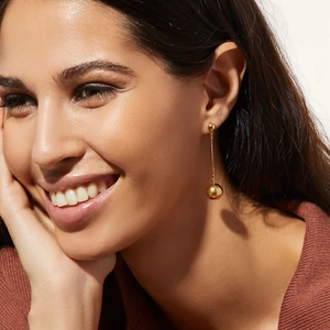 18K gold titanium steel drop earrings with spherical pendants worn by a female model