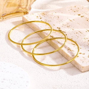 Three-piece set of gold minimalist bangles with polished and matte frosted finishes