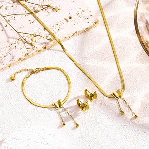 Gouden vlinder sieradenset met slangenketting en kwastjesoorbellen op een stenen basis