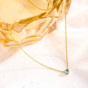 Close-up of heart-shaped blue birthstone pendant on gold stainless steel chain