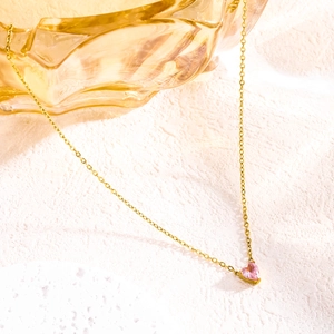 Close-up of golden heart pendant necklace featuring a polished pink zircon heart stone