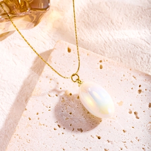 Minimalist gold necklace with oval opal-like resin pendant on natural stone surface