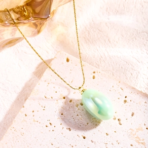 Close-up of a gold titanium necklace with an elegant oval green resin pendant on stone