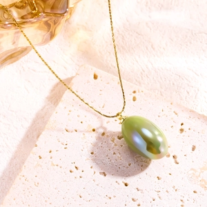 Detailed macro view of olive green oval resin pendant on a gold titanium steel necklace