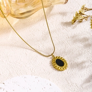 Detail of vintage gold plated snake chain necklace with black oval floral pendant