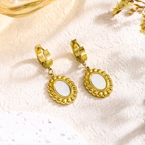 Detail of vintage gold plated oval earrings with white shell inlay and beaded edges