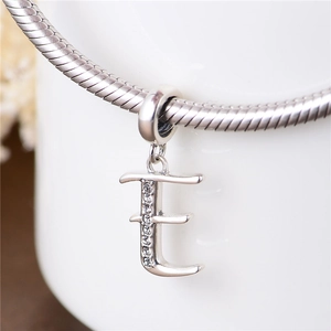 Primer plano del dije letra E de plata S925 con cristales en pulsera de cadena serpiente
