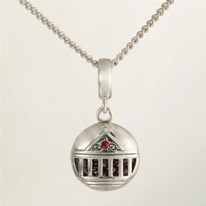 Macro shot of silver architectural globe charm with red gemstone and purple crystals