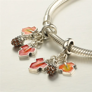 Détail du bracelet argenté avec feuilles d'érable en émail rouge et glands en cristal