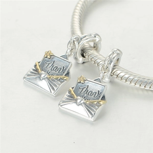 Détail macro de charms enveloppe en argent S925 avec accents dorés et gravure