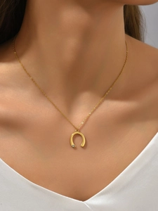 Close-up of golden U-shaped horseshoe necklace with diamond accent worn by model