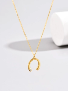 Macro detail of gold U-shaped pendant with a sparkling white diamond on a fine chain