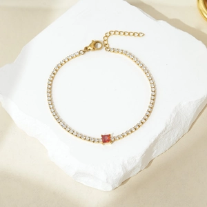 Elegante bracciale in acciaio titanio dorato con pavé di zirconi e gemma rossa quadrata