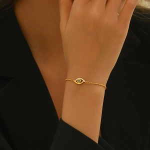 Elegant gold Evil Eye beaded bracelet with crystal accents on a black suit background