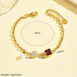 Dettaglio del bracciale dorato con rubino quadrato, perla e ciondoli con cristalli