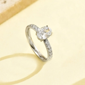 Detailed macro view of an oval-cut diamond ring with a pavé band on a stone base