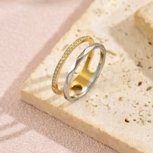 Zweifarbiger Edelstahlring mit geometrischen Facetten und Zirkonia-Pavé auf Steinoberfläche