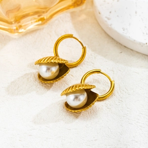 Elegante goldene Muschel-Creolen mit weißen Perlen auf minimalistischem weißem Steinboden