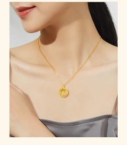 Detail view of a circular gold dreamcatcher pendant necklace on a champagne silk garment