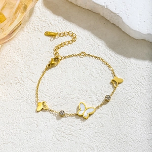 Gold butterfly bracelet with white shell and zircons on textured white background