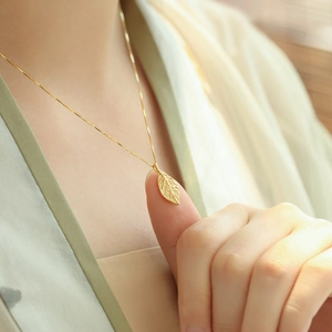 Elegante ciondolo a foglia da donna con zirconi micro-pave su una catena dorata classica