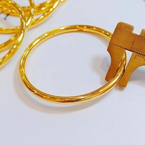 Dettaglio di un bracciale rigido in acciaio al titanio dorato misurato con un calibro