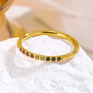 Eleganter Edelstahlring in Gold mit bunten Regenbogen-Edelsteinen auf weißem Stein