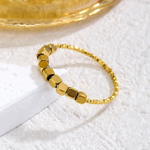 Elegant gold plated open ring with square beads and matte texture on stone stand