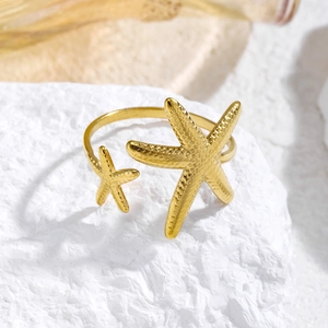 Detalle de anillo de estrella de mar dorada con textura sobre fondo de piedra blanca