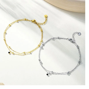Detail of double-layer gold and silver anklets with black zircon charms and ball beads