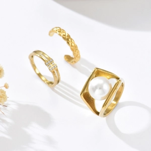 Detailansicht eines 3-teiligen Goldrings-Sets mit Perle und gestepptem Rautenmuster