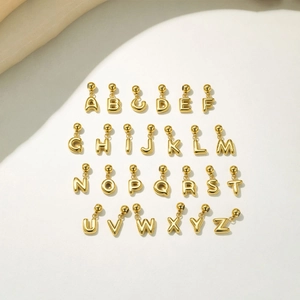 Vue macro de 26 mini pendentifs lettres bulles en acier inoxydable plaqué or