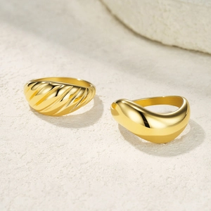 Detailed view of gold croissant textured and smooth polished wide bands on stone surface