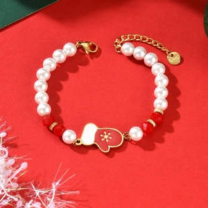 Christmas pearl bracelet with red beads and Santa glove charm on festive red background