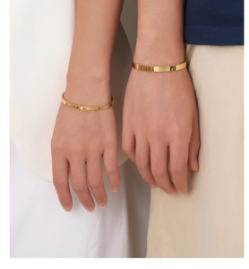 Close-up of a minimalist gold C-shaped titanium steel bracelet on a model wrist