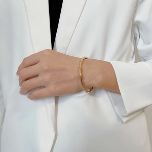 Bracelet jonction bambou doré porté avec un blazer blanc pour un look chic minimaliste
