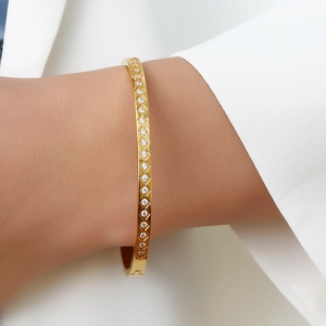 Detailed view of a gold bangle featuring a lattice pattern and sparkling zircon stones
