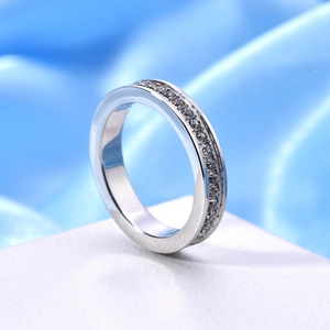 Elegante anello in acciaio argento con zirconi pavé su tessuto di seta blu lucido