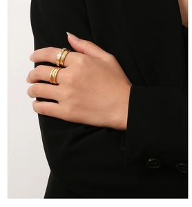 Detail van gestapelde gouden ringen met bladstructuur en geometrische patronen op model